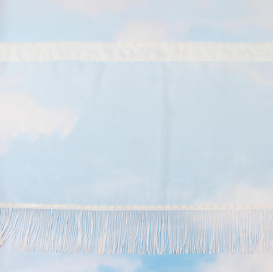 Val van offwhite vitragestof met een fijn streeppatroon en een rechte franjeband van ongeveer 15 cm.